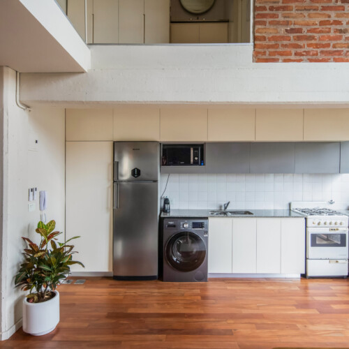 Remodelación de departamento tipo loft en CABA estilo industrial y moderno. Materiales de ladrillo visto, madera y herrería. Sector de cocina, muebles laqueados.