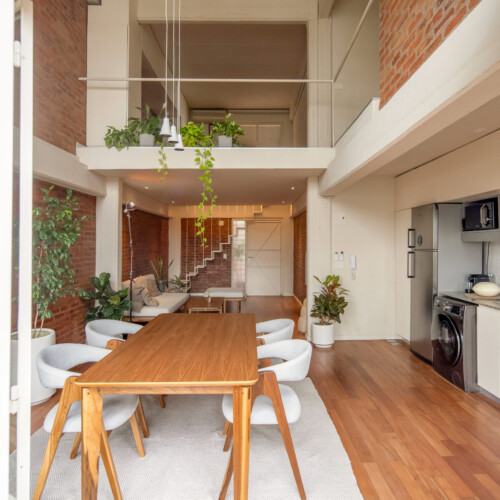Remodelación de departamento tipo loft en CABA estilo industrial y moderno. Estar comedor con doble altura. Materiales de ladrillo visto, madera y herrería