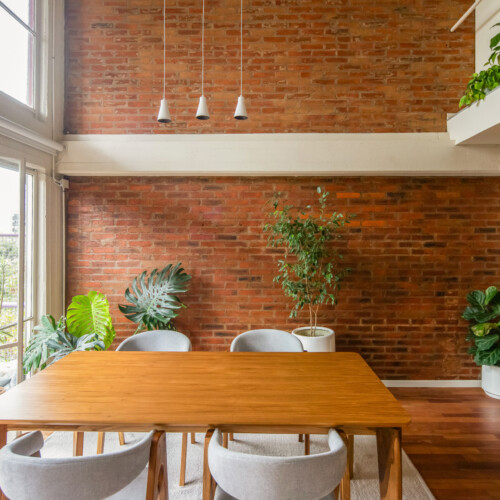 Remodelación de departamento tipo loft en CABA estilo industrial y moderno. Estar comedor con doble altura. Materiales de ladrillo visto, madera y herrería